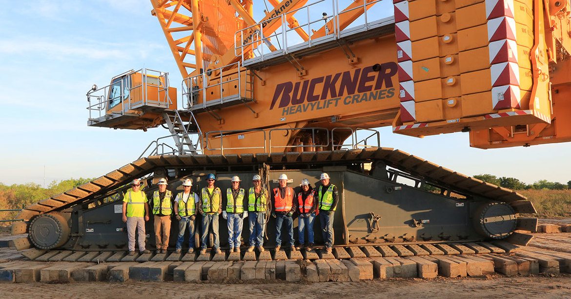 group of construction workers standing in tracks of crane