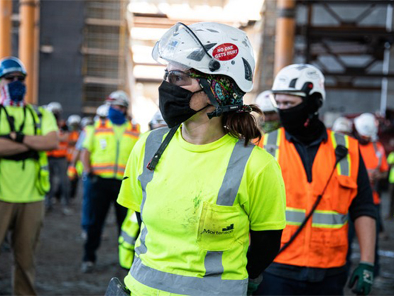 construction woman with mask on in front of craft team members